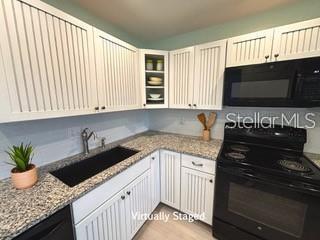 kitchen featuring white cabinets, black appliances, sink, and light stone counters