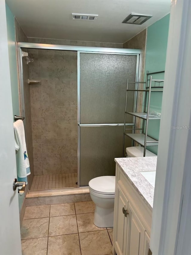 bathroom featuring vanity, tile patterned floors, toilet, and a shower with door