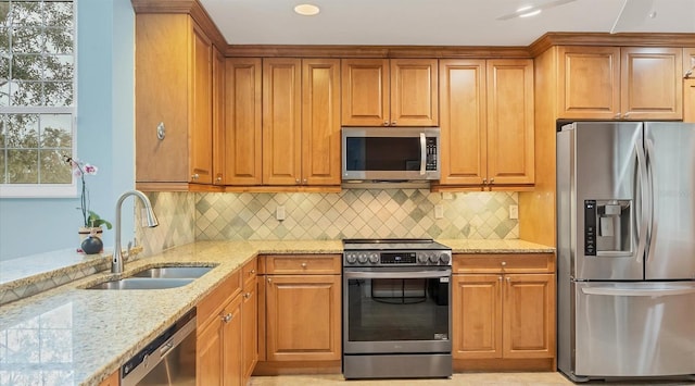 kitchen featuring light stone countertops, backsplash, stainless steel appliances, and sink