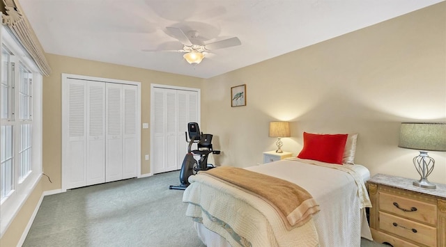 bedroom with multiple closets, ceiling fan, and dark colored carpet