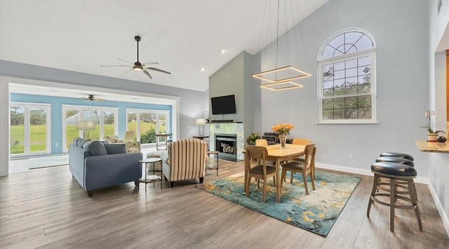 dining space featuring hardwood / wood-style flooring, high vaulted ceiling, and ceiling fan