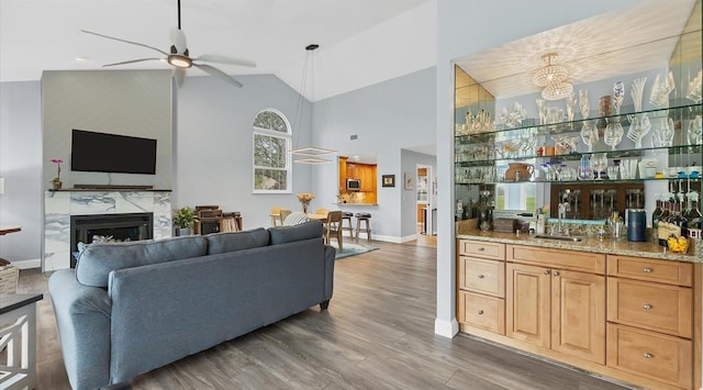 living room featuring sink, vaulted ceiling, ceiling fan, a fireplace, and wood-type flooring