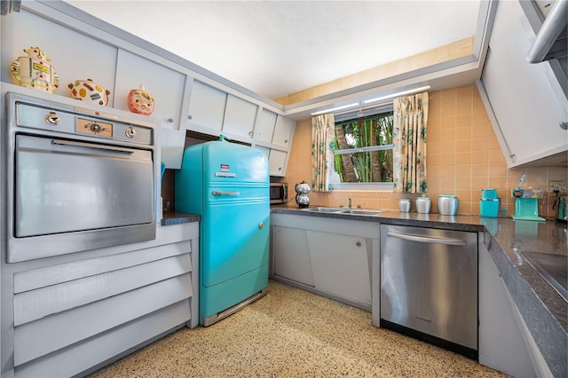 kitchen featuring white cabinets, sink, appliances with stainless steel finishes, and tile walls