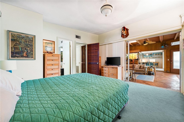 carpeted bedroom featuring a closet, beamed ceiling, and wooden walls