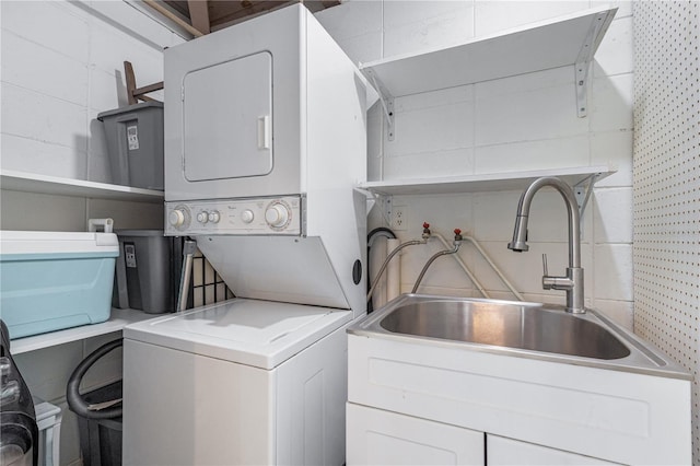 washroom with stacked washer and clothes dryer and sink