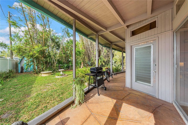 unfurnished sunroom featuring vaulted ceiling with beams