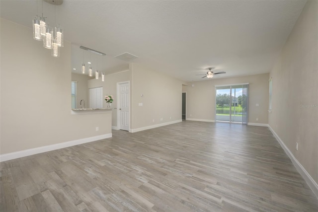 unfurnished living room featuring ceiling fan, sink, and light hardwood / wood-style flooring