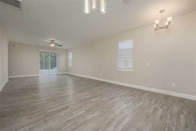 spare room featuring ceiling fan with notable chandelier, a textured ceiling, and light hardwood / wood-style flooring