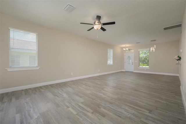 spare room with hardwood / wood-style floors and ceiling fan with notable chandelier