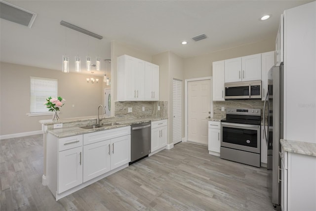 kitchen with stainless steel appliances, white cabinetry, and pendant lighting