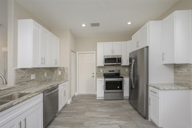 kitchen featuring white cabinets, appliances with stainless steel finishes, and light hardwood / wood-style flooring