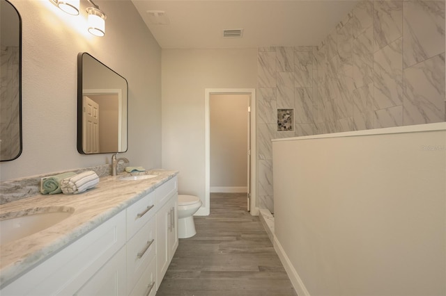 bathroom featuring tiled shower, hardwood / wood-style floors, vanity, and toilet