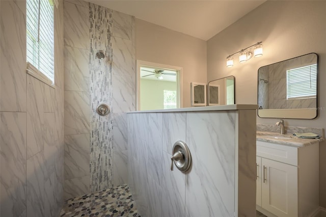 bathroom with ceiling fan, vanity, and a tile shower