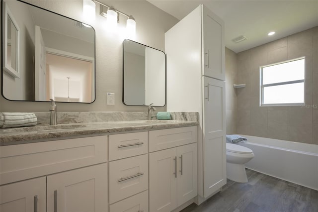 full bathroom featuring toilet, tiled shower / bath combo, vanity, and wood-type flooring