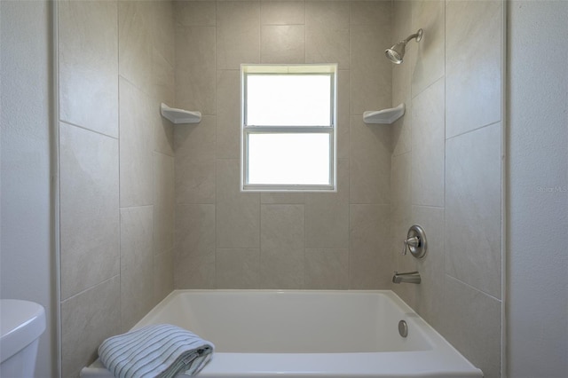 bathroom featuring tiled shower / bath and toilet