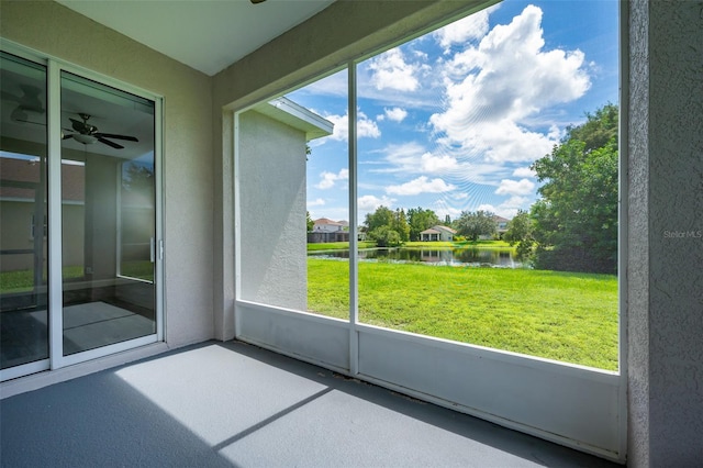 unfurnished sunroom featuring a water view, ceiling fan, and plenty of natural light