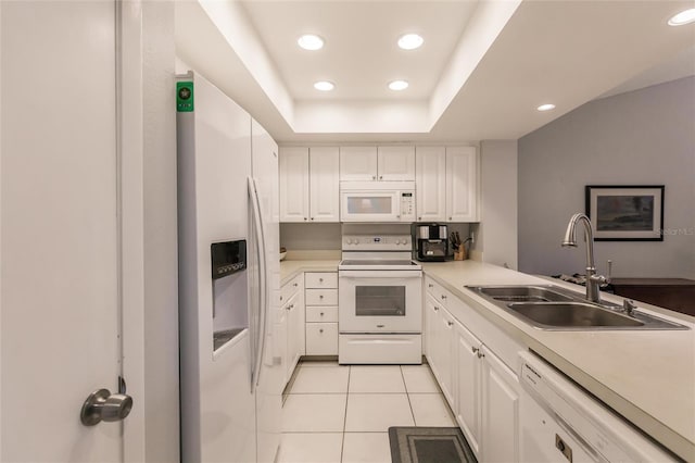 kitchen with white cabinets, sink, light tile patterned flooring, a tray ceiling, and white appliances