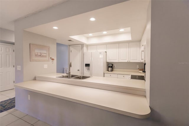 kitchen featuring sink, light tile patterned flooring, a tray ceiling, white cabinetry, and white appliances