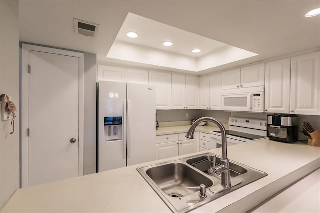 kitchen with white cabinetry, a raised ceiling, sink, and white appliances