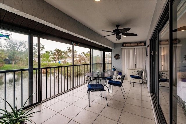 unfurnished sunroom featuring a water view and ceiling fan