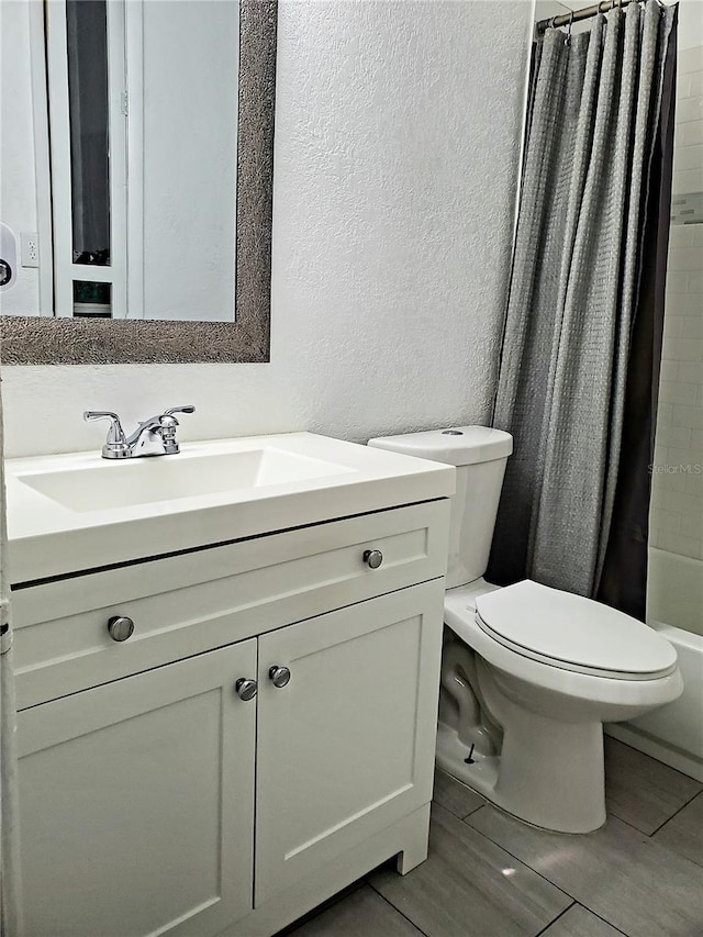 full bathroom with tile patterned flooring, shower / tub combo, vanity, and toilet