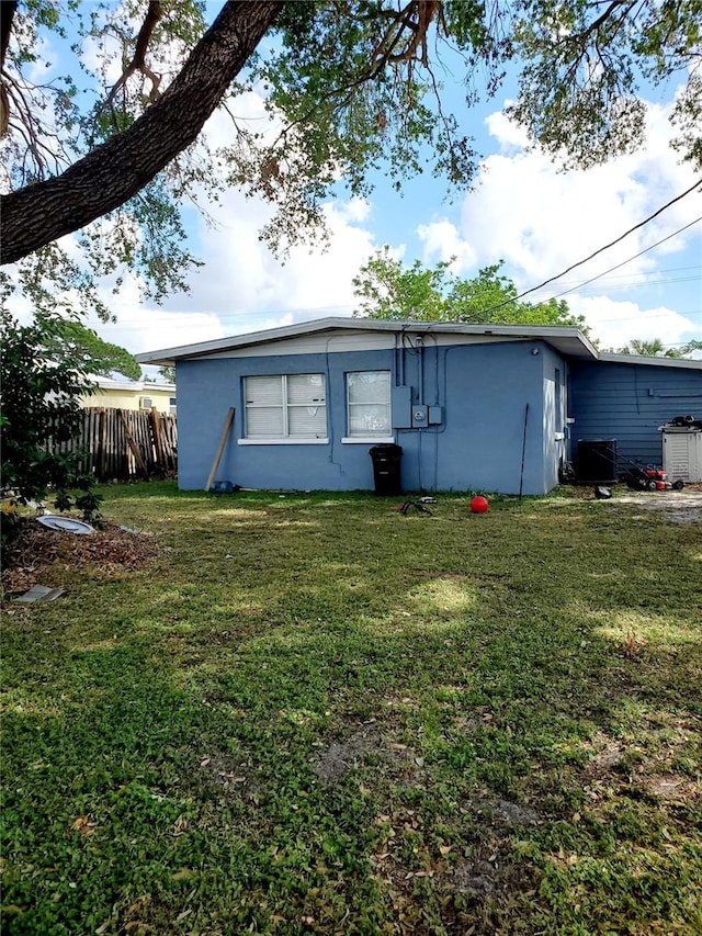 rear view of property featuring a yard and cooling unit