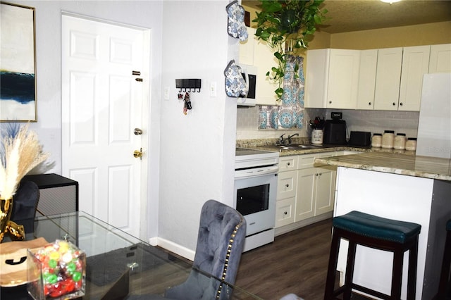 kitchen featuring dark hardwood / wood-style floors, white cabinetry, white appliances, and backsplash