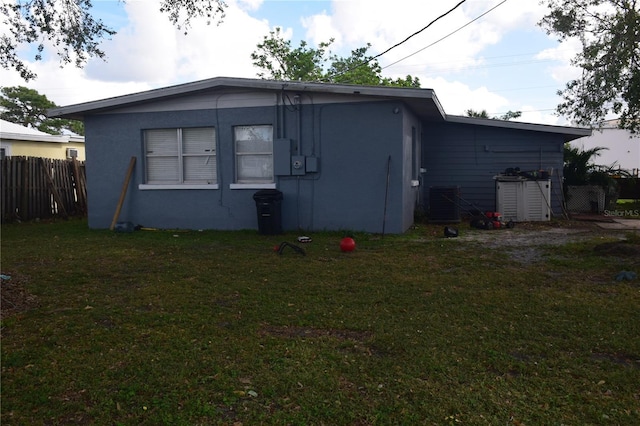 rear view of house featuring central air condition unit and a lawn