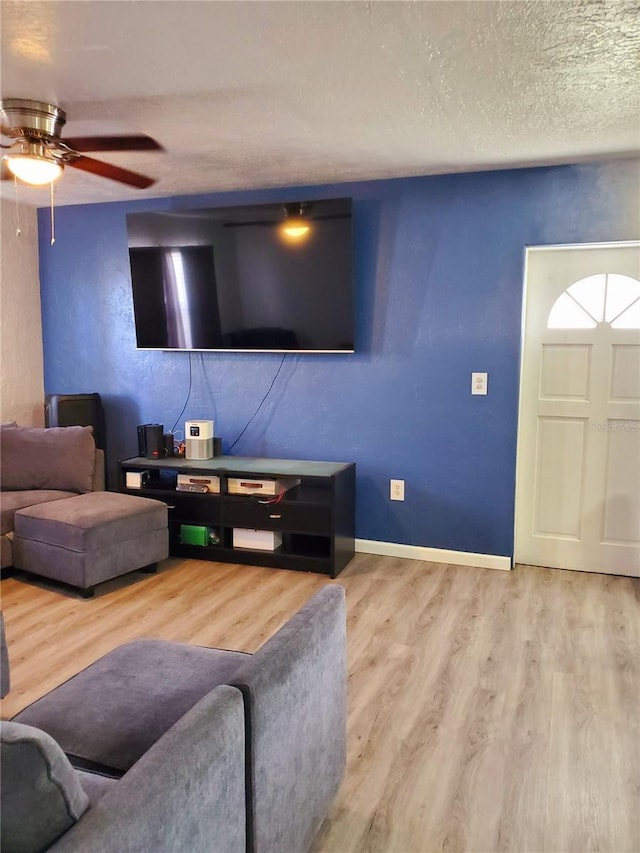 living room with ceiling fan, a textured ceiling, and hardwood / wood-style flooring