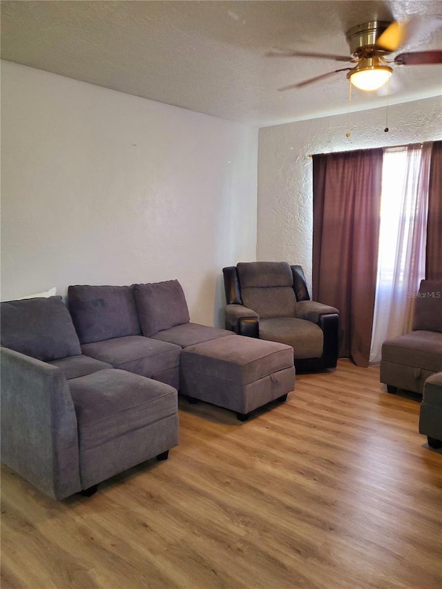 living room with wood-type flooring, a textured ceiling, and ceiling fan