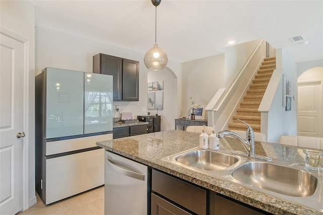 kitchen featuring appliances with stainless steel finishes, dark brown cabinets, light tile patterned floors, pendant lighting, and sink