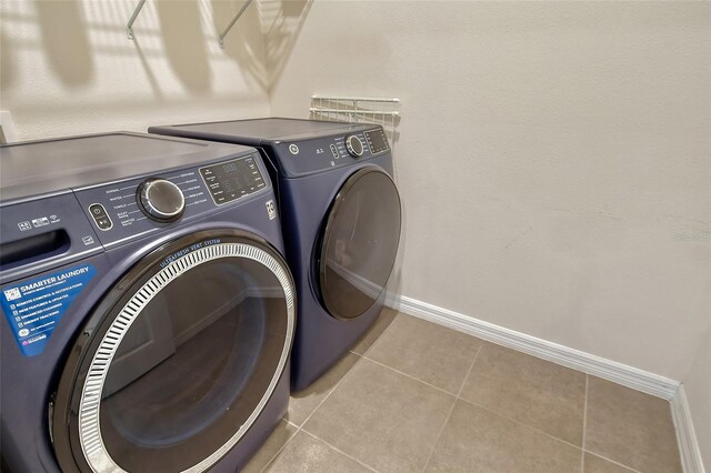 clothes washing area with washer and clothes dryer and light tile patterned floors