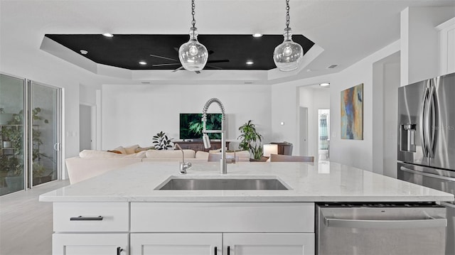 kitchen featuring white cabinets, sink, appliances with stainless steel finishes, a tray ceiling, and decorative light fixtures