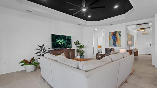 living room with a tray ceiling, ceiling fan, and light tile patterned floors