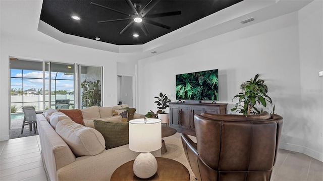 living room featuring ceiling fan and a raised ceiling