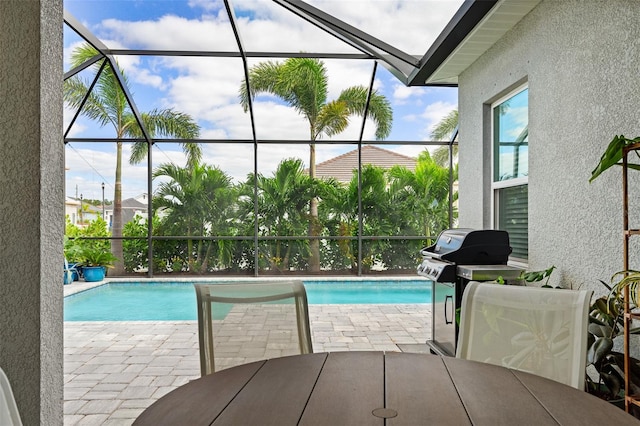 view of swimming pool featuring glass enclosure, grilling area, and a patio area