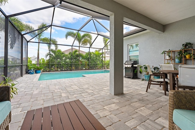 view of pool with glass enclosure, a grill, and a patio area