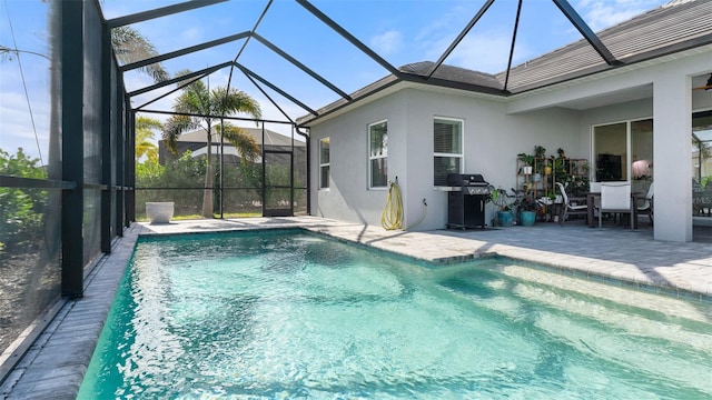 view of swimming pool featuring glass enclosure, a patio area, and grilling area