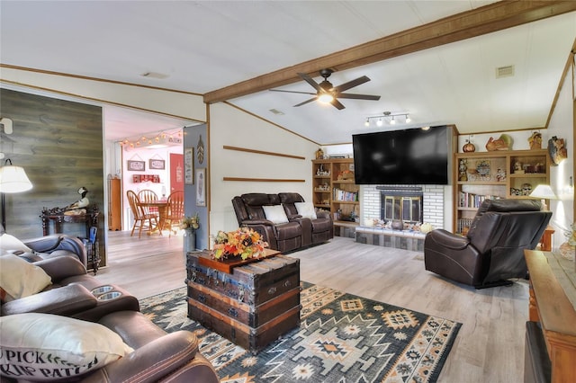 living room featuring ceiling fan, wooden walls, wood-type flooring, lofted ceiling with beams, and a fireplace