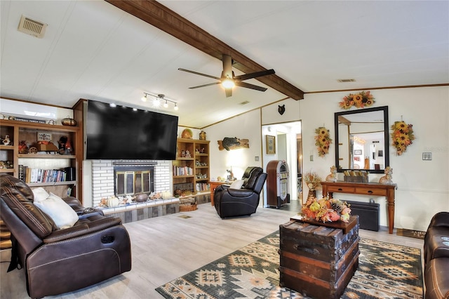 living room with lofted ceiling with beams, light hardwood / wood-style floors, ceiling fan, and a brick fireplace
