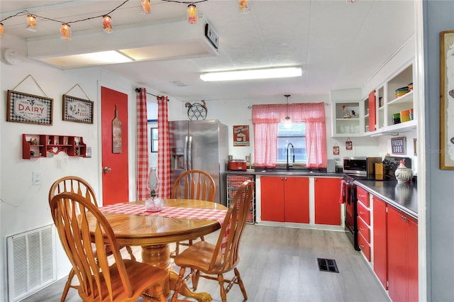 kitchen featuring black / electric stove, stainless steel fridge with ice dispenser, sink, and light hardwood / wood-style flooring