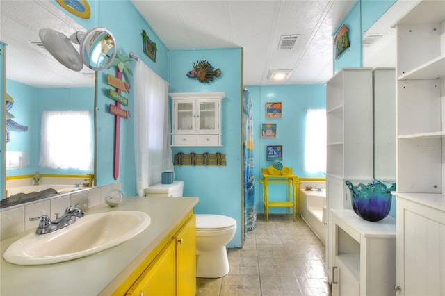 bathroom featuring vanity, a tub to relax in, and toilet