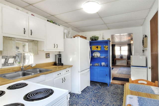 kitchen with white appliances, white cabinetry, a drop ceiling, and sink