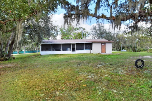 rear view of house with a sunroom and a yard