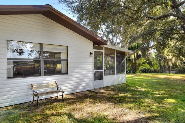 view of side of property featuring a sunroom and a lawn