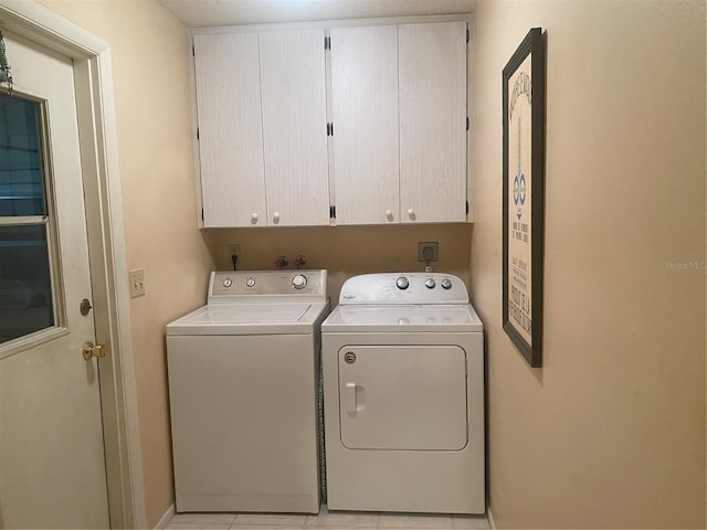 clothes washing area with cabinets, independent washer and dryer, light tile patterned floors, and a textured ceiling