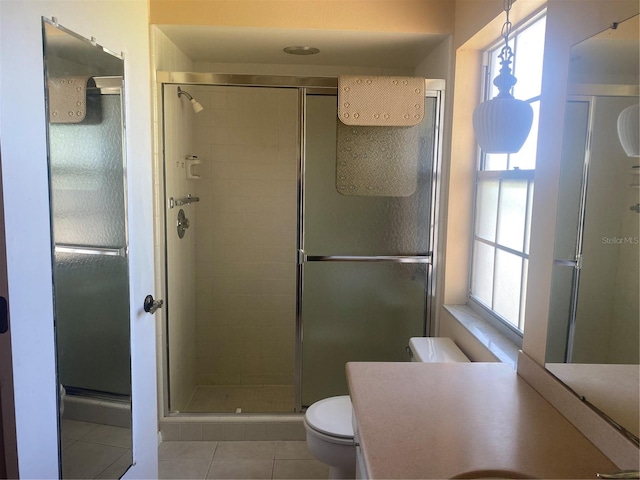 bathroom with a shower with shower door, a healthy amount of sunlight, tile patterned floors, and toilet