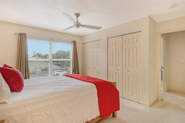 bedroom with carpet floors, ceiling fan, and multiple closets