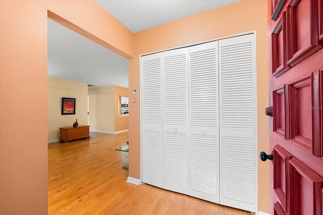 corridor with light hardwood / wood-style floors and a textured ceiling