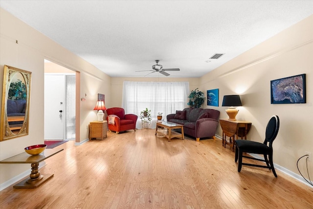 living room with ceiling fan, a textured ceiling, and light hardwood / wood-style flooring